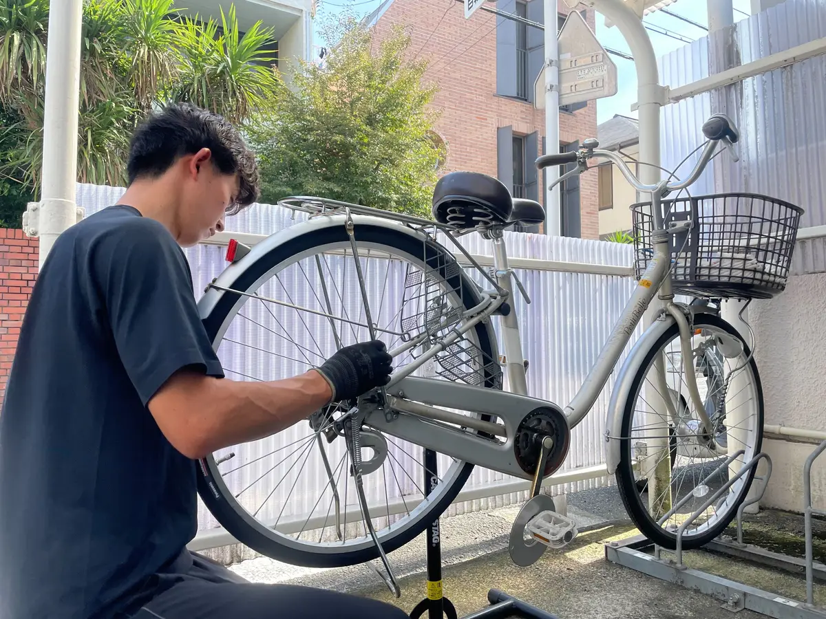 出張先で自転車の後輪を整備するスタッフ